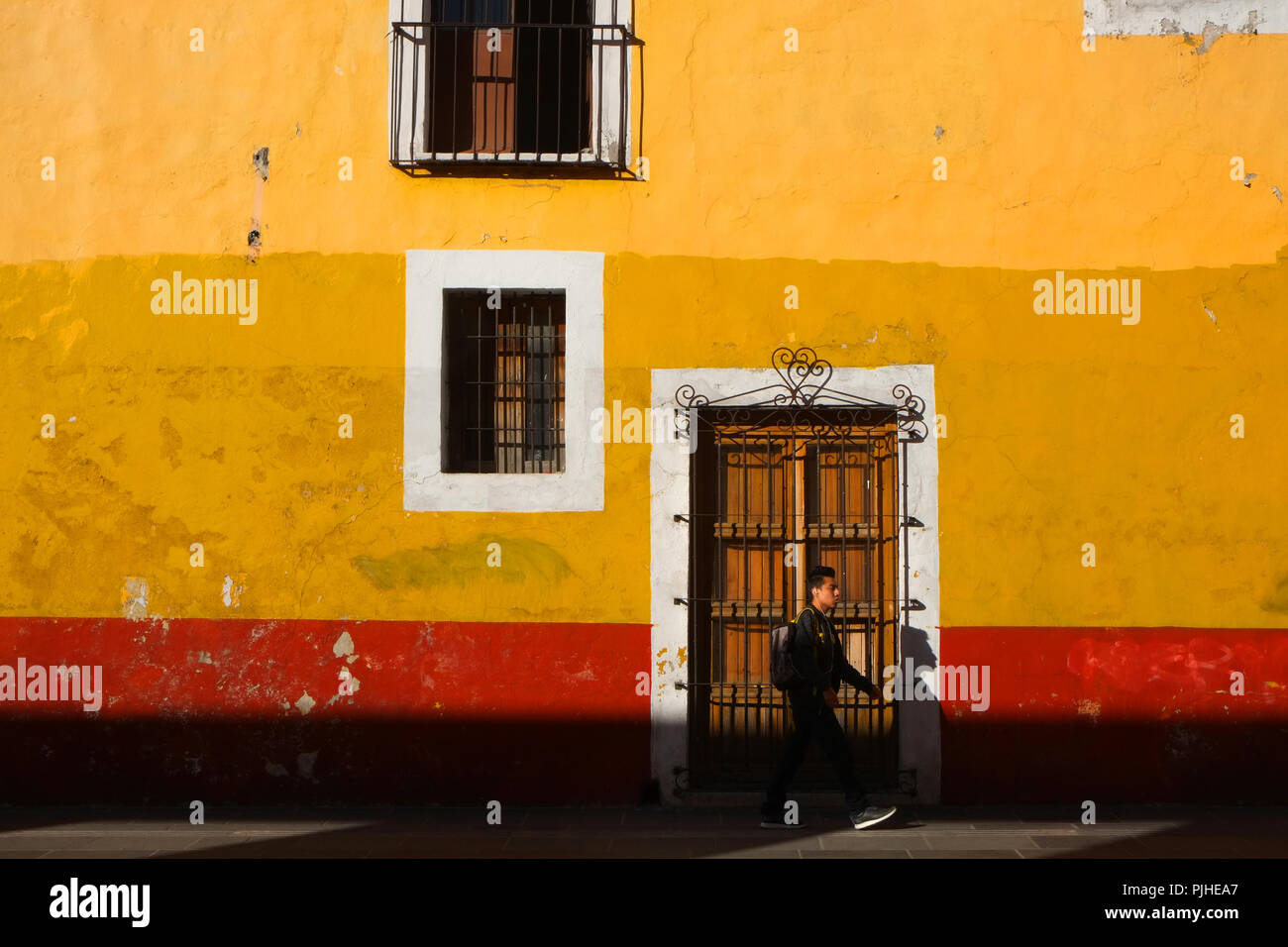 Leuchtend rote und gelbe Wand im frühen Morgenlicht, Puebla, Mexiko Stockfoto