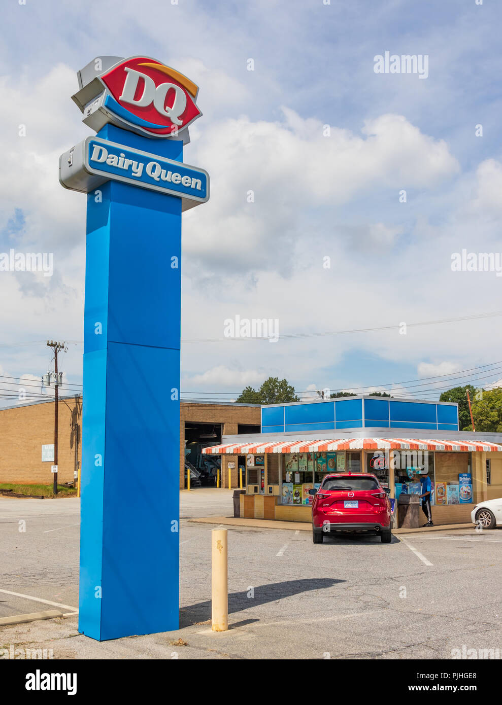 HICKORY, NC, USA -9/6/18: ein 1950s-era Dairy Queen Gebäude und modernere street sign. Ein junger Mann reinigt Windows. Stockfoto