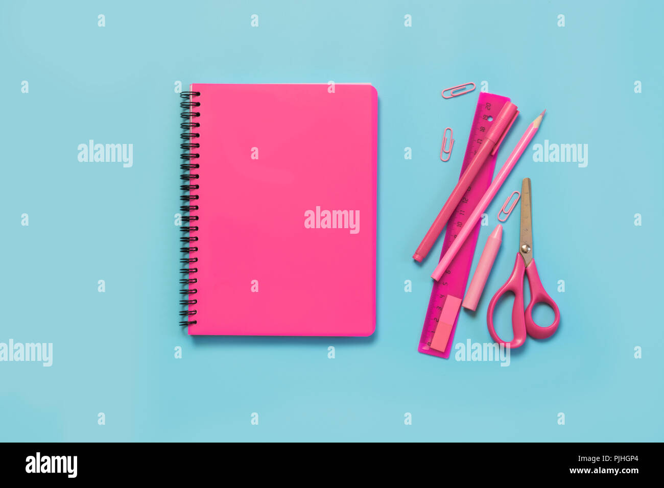 Rosa mädchenhafte Schulmaterial, Hefte und Stifte auf druckvolle Blau. Ansicht von oben, flach. Kopieren Sie Platz. Stockfoto