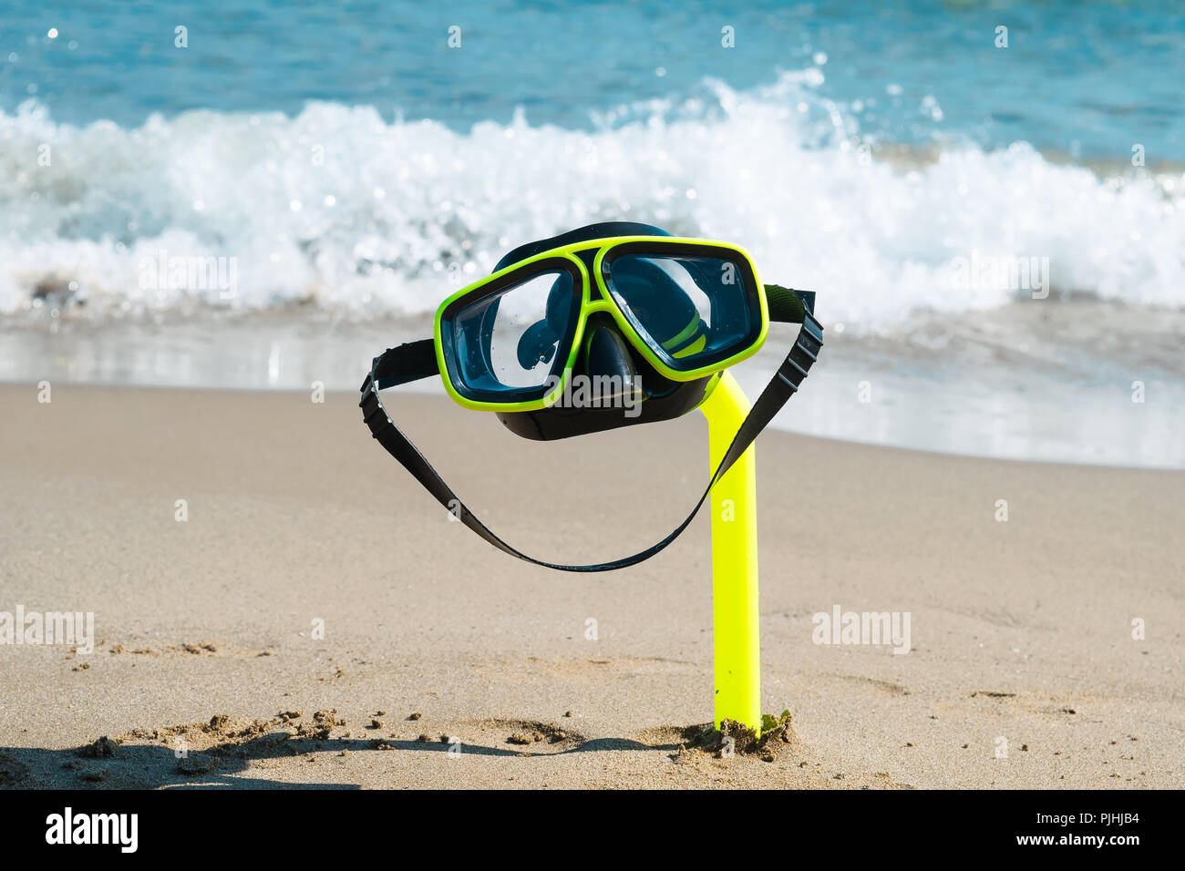 Eine Taucherbrille und Schnorchel am Sandstrand mit Blick auf das Meer im Hintergrund Stockfoto