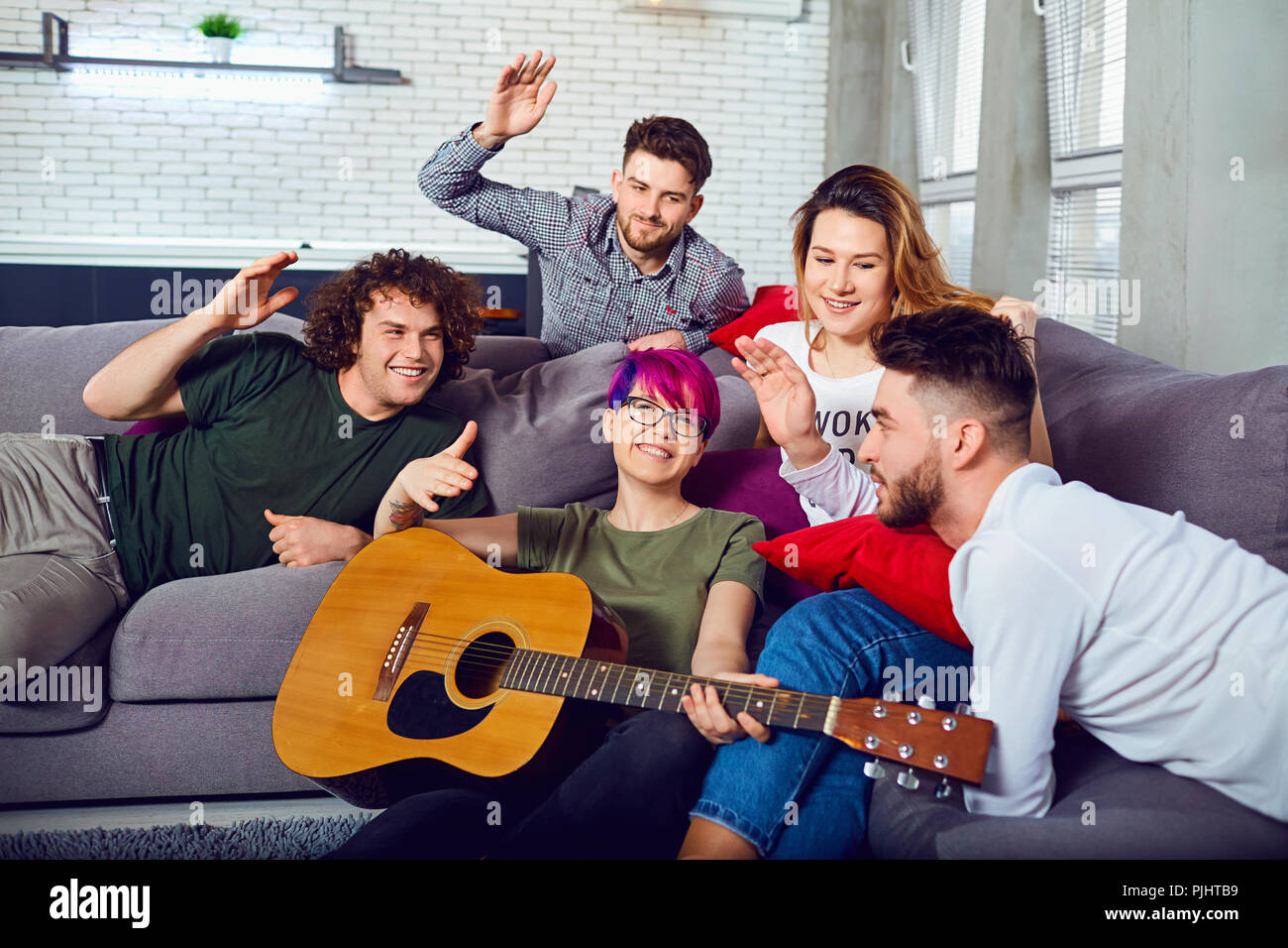 Eine Gruppe von Freunden mit einer Gitarre auf einer Party in einem Raum. Stockfoto
