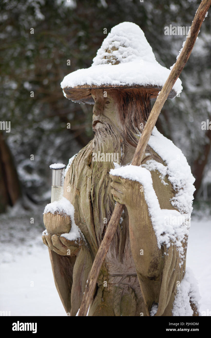 Fantasy-Kettensägen-Holzschnitzerei des orientalischen Mannes im Schneehöden mit Stab und Flasche Trank Stockfoto