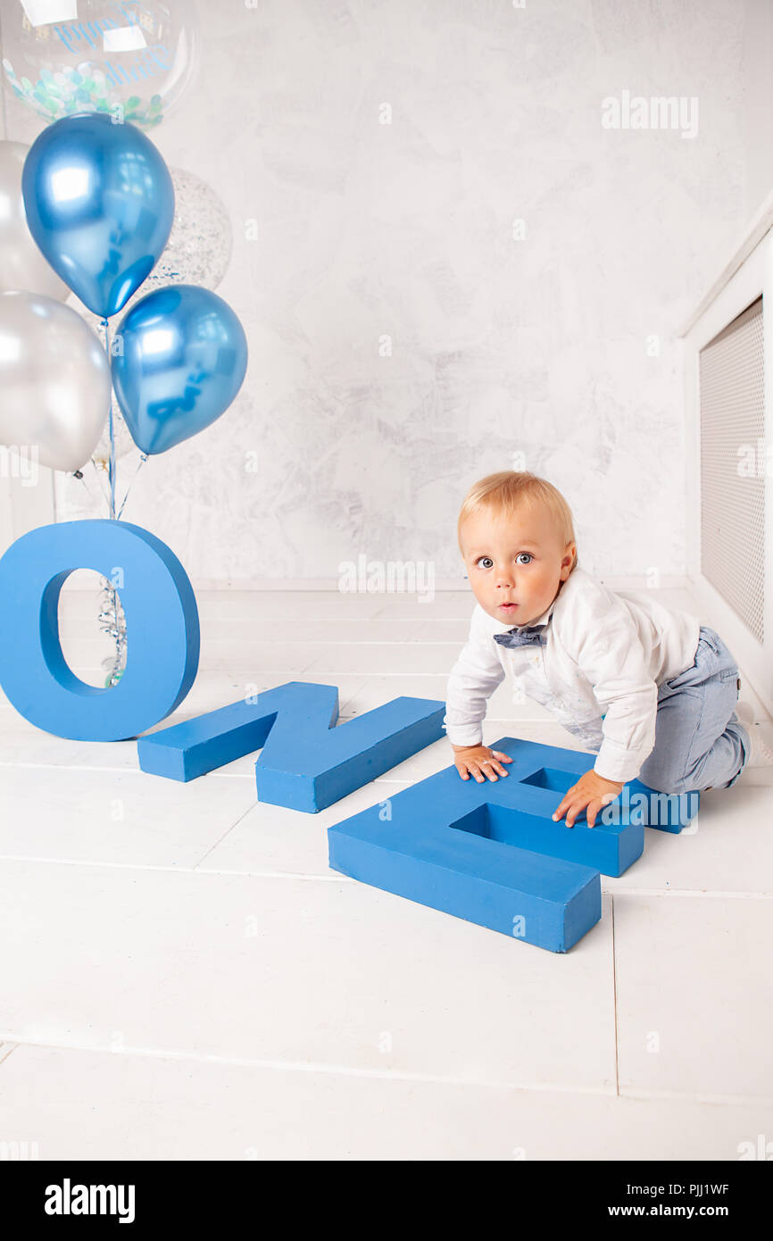 Portrait von Fashion lustige kleine Junge im Studio mit großen blauen Buchstaben, Luftballons und Kuchen Stockfoto