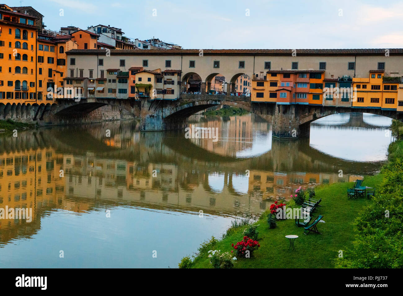 Ponte Vechio die berühmteste Brücke und touristische Attraktion in Florenz spiegelt sich im stillen Wasser der Fluss Arno mit Architektur entlang des Flusses Stockfoto