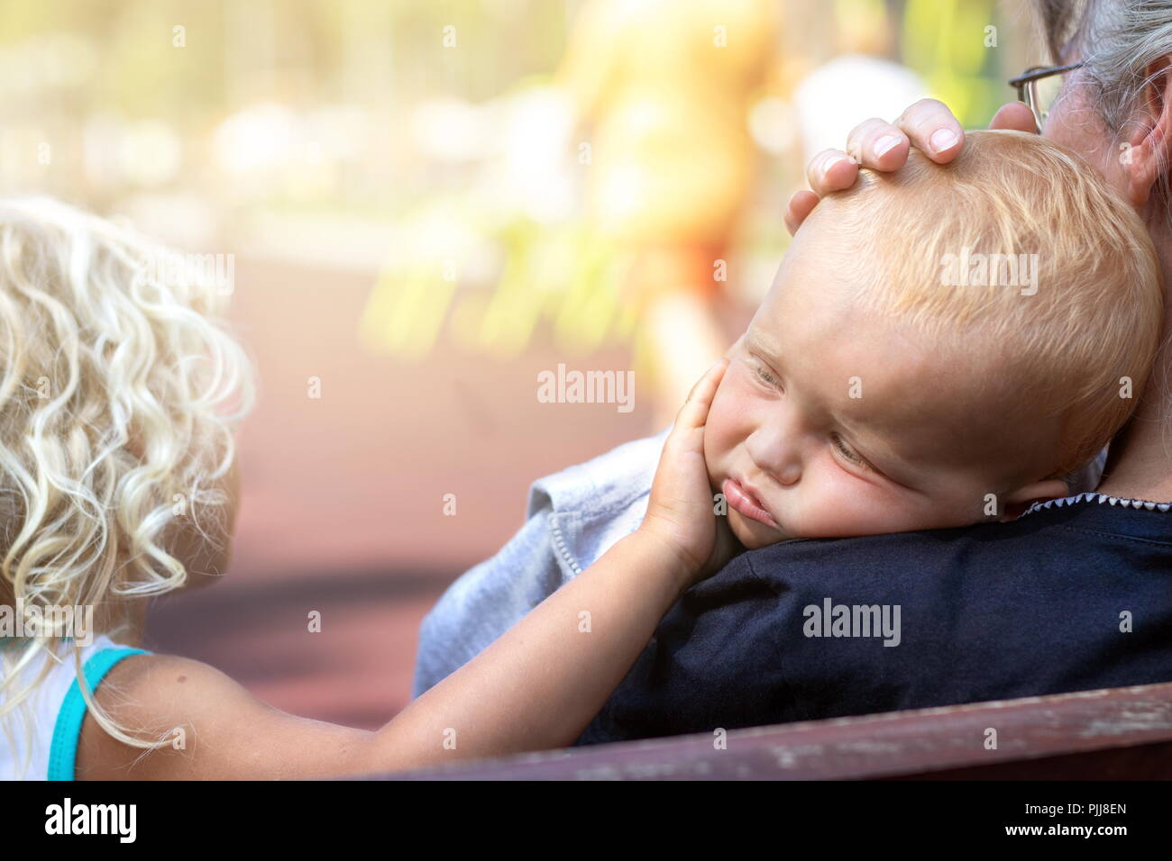 Großmutter und Schwester umarmen und Komfort das Umkippen Kind auf dem Spielplatz Stockfoto
