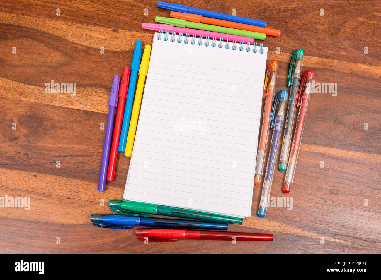 Spiralbindung gesäumt notepad durch verschiedenfarbige Stifte umgeben Stockfoto