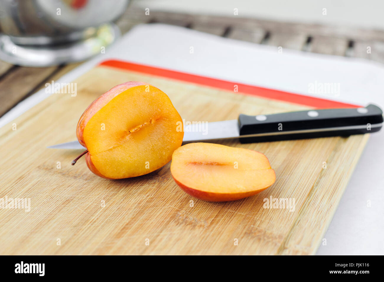 Ein Schnitt öffnen Amigo pluot Früchte auf einem Holz Schneidebrett Stockfoto