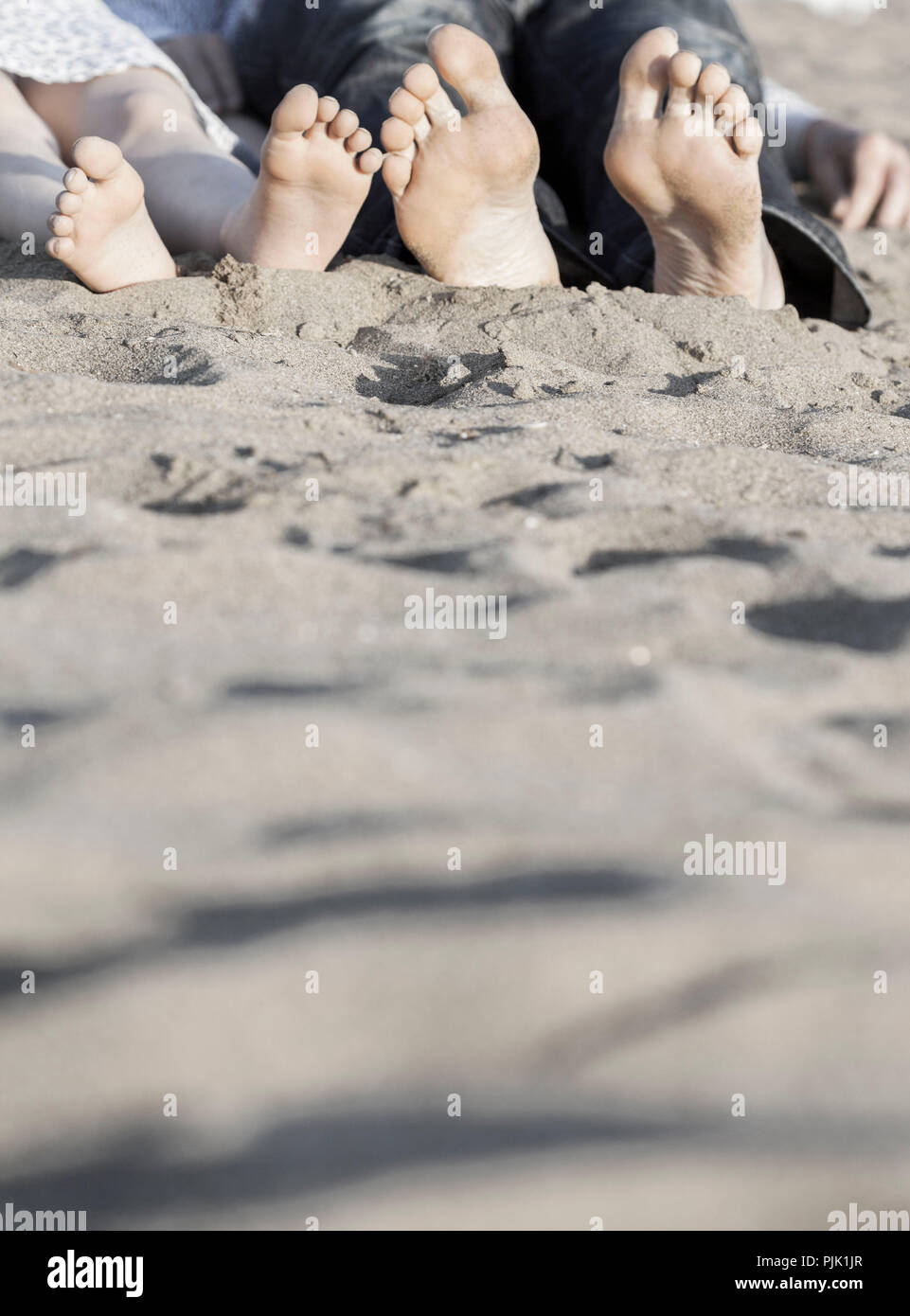 Vater und Tochter liegen in den Sand, Sohlen auf die Kamera zu, Detail Stockfoto