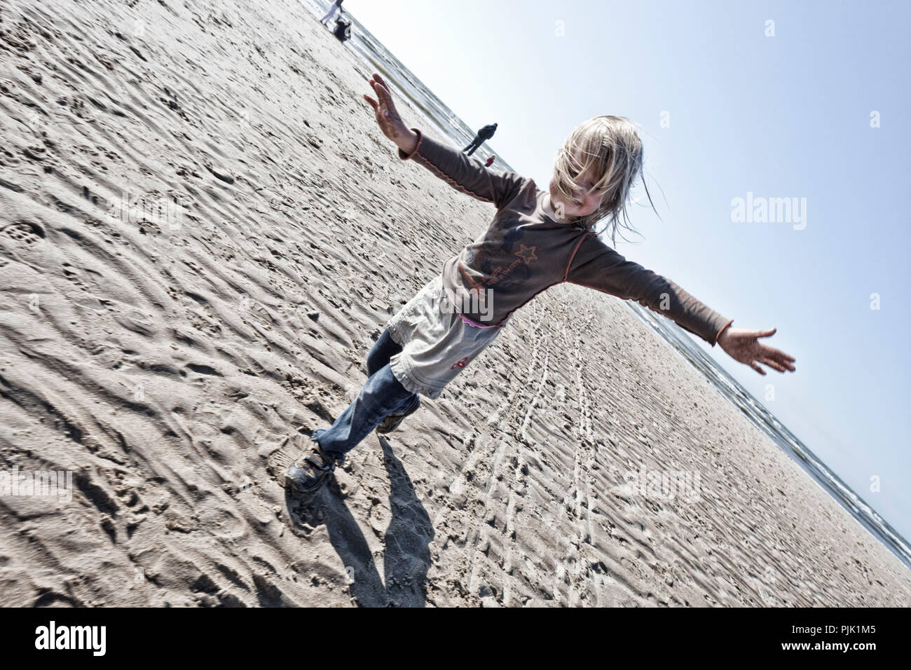 Mädchen läuft mit ausgestreckten Armen am Strand Stockfoto