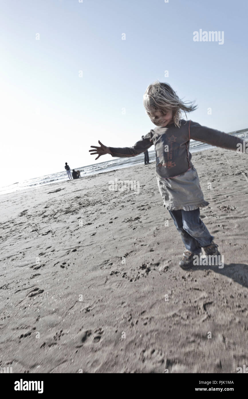 Mädchen läuft mit ausgestreckten Armen am Strand Stockfoto