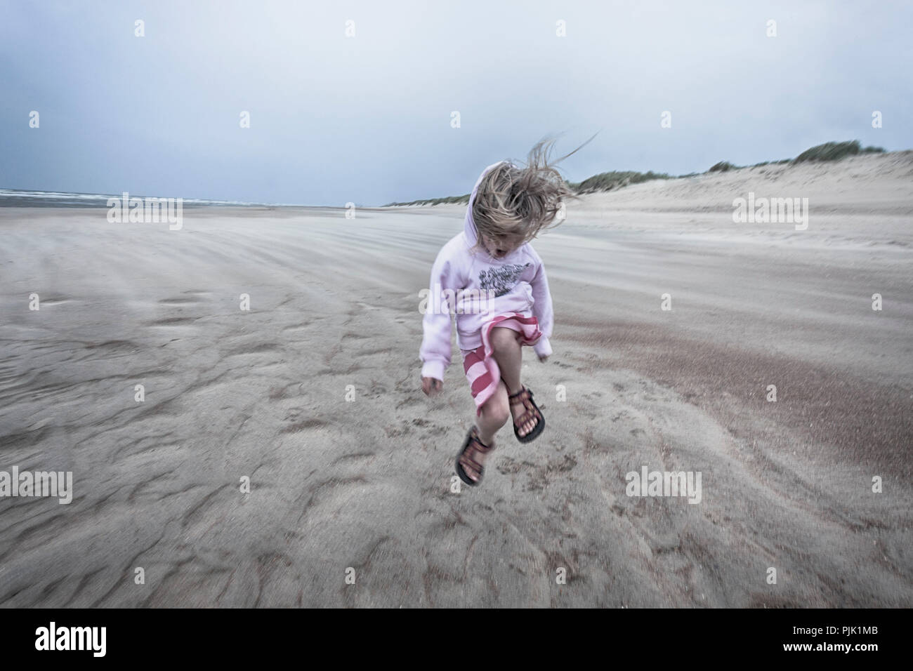 Mädchen ist der Sprung auf den Strand Stockfoto