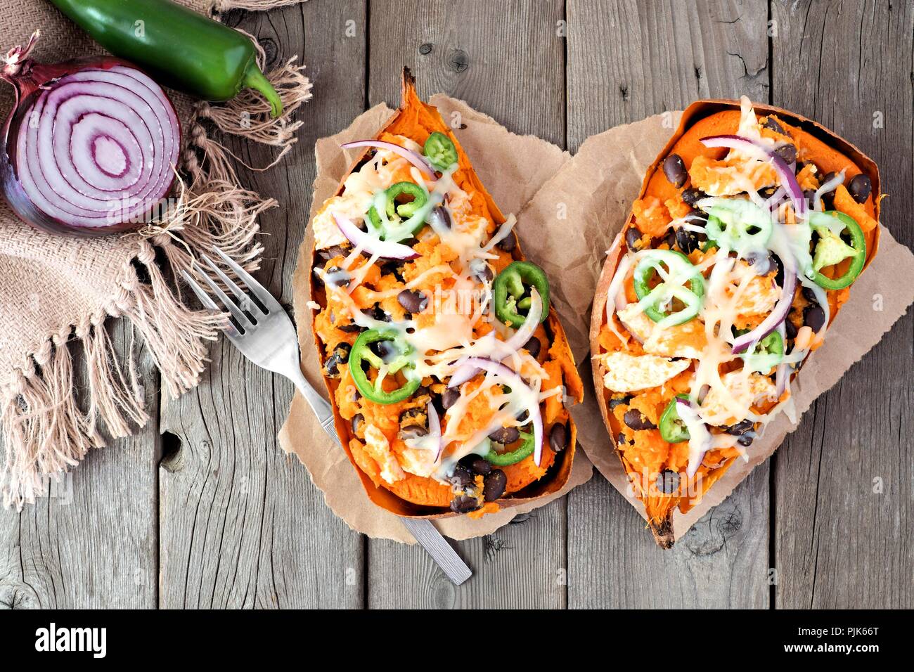 Gebackene süsse Kartoffeln gefüllt mit Hühnerfleisch, Gemüse und Käse, oben Blick auf eine rustikale Holz Hintergrund Stockfoto