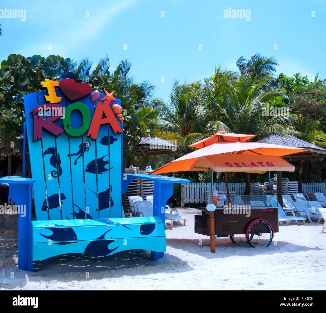 West Bay, Roatan, Honduras - April 7, 2017: West Bay Beach mit einem großen blauen Stuhl und Eisdiele Stockfoto