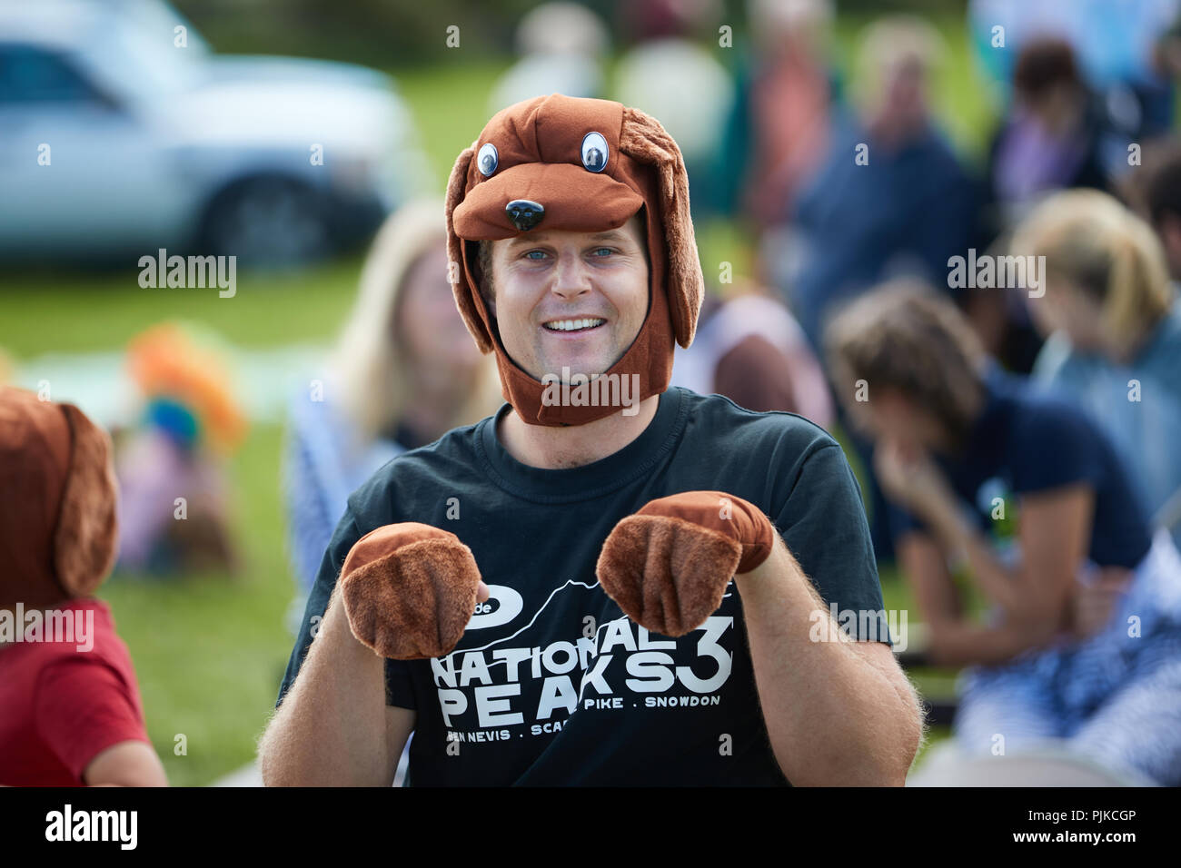 Der Mensch verhält sich wie ein kleiner brauner Hund in einem Hund Kostüm im Tiefland Spiele, Thorney, Somerset, England Stockfoto