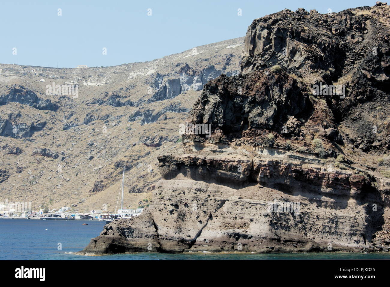 Griechenland, die charmante Insel Thirasia. Dramatische vulkanische Felsformationen. Blick auf schroffe, zerklüftete Klippen, die aus der Ägäis emporragen. Stockfoto