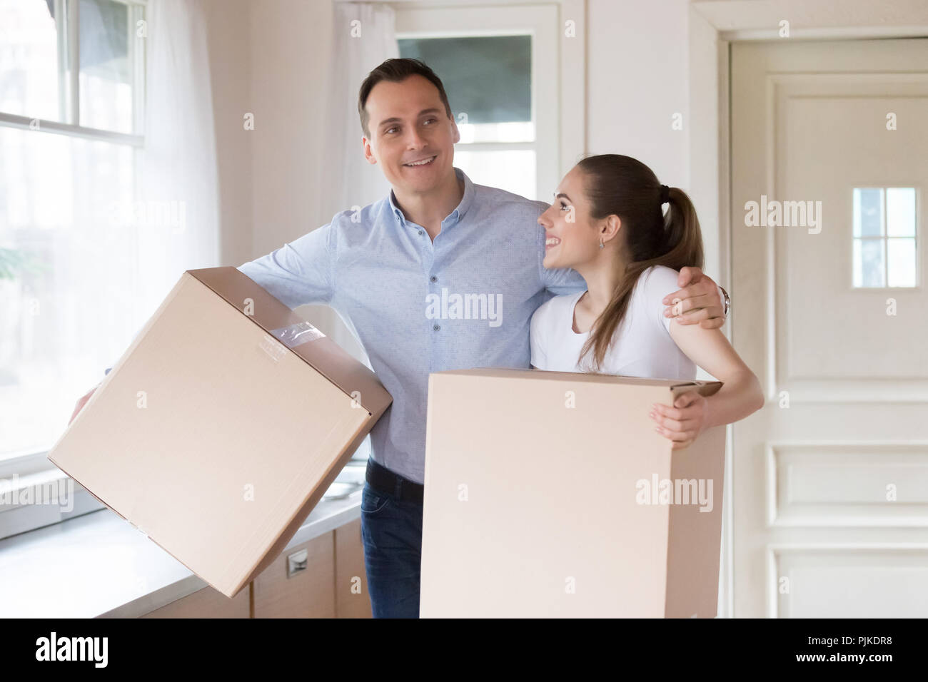 Aufgeregt Paar hält Kartons Eingabe von eigenen Haus Stockfoto