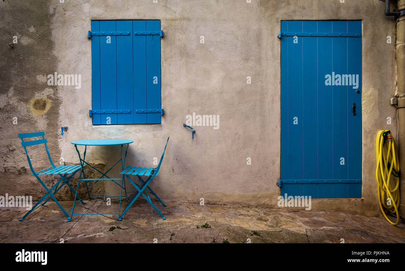 Tisch und Stühle vor der Hausfassade, Tür- und Shutter in Blau, Bages Stockfoto