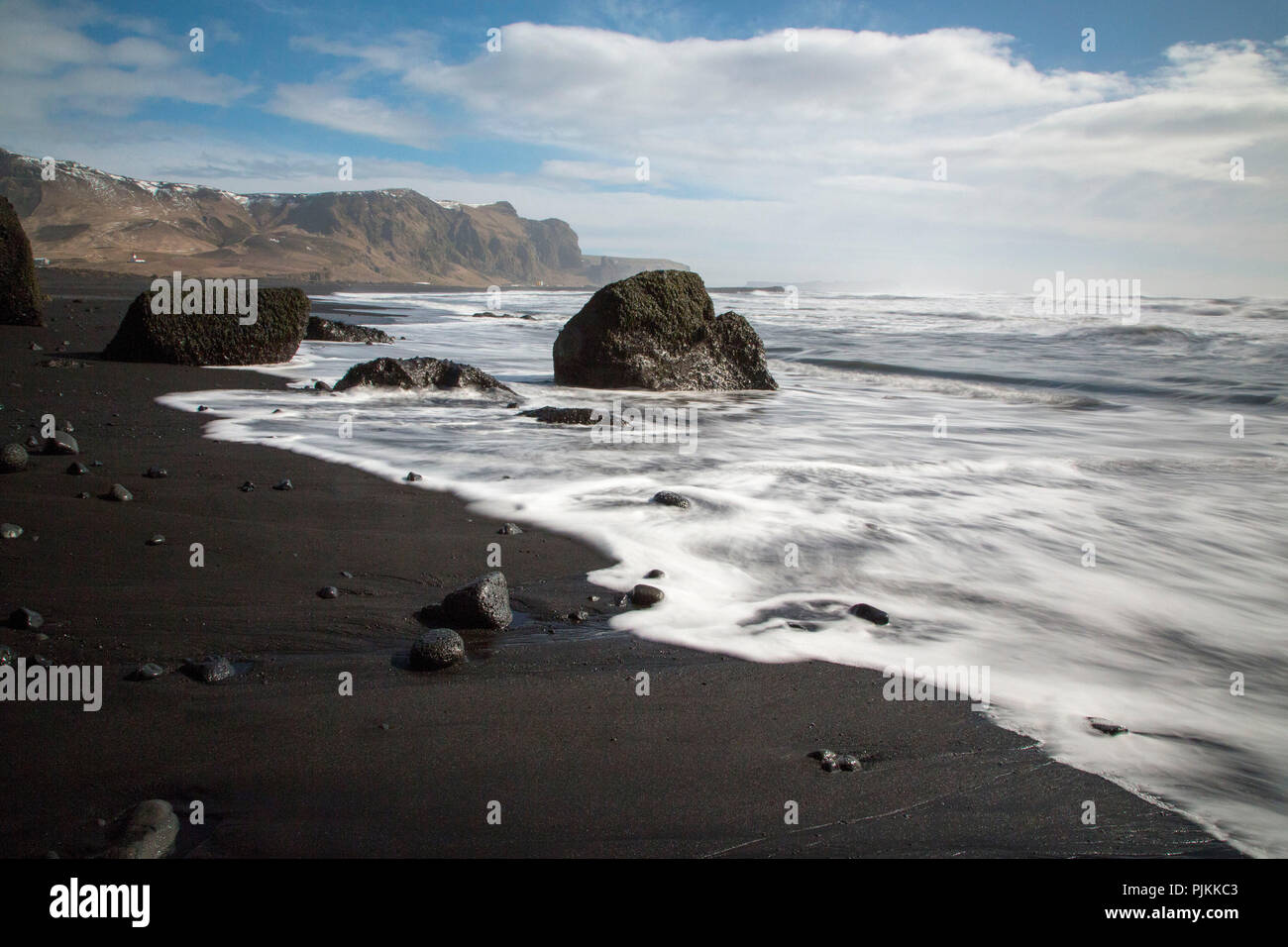 Island, Vik an der Südküste, schwarzen Strand, schwarze Felsen, weißer Schaum, blauer Himmel Stockfoto