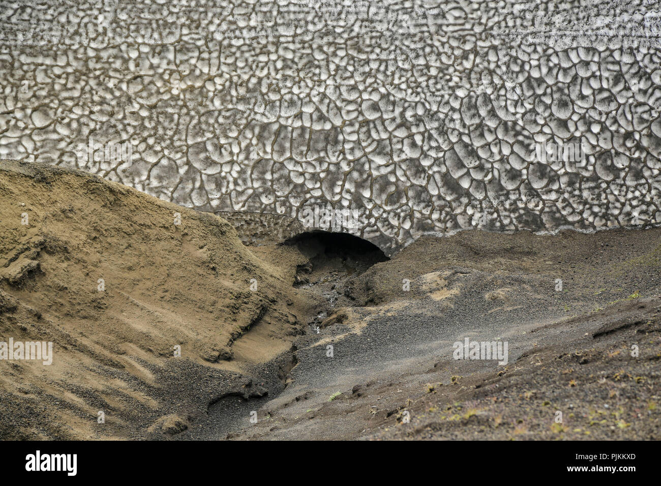 Island, Fjallabak, Schnee, Feld, alte Schnee auf Lavasand, mit vulkanischer Asche im Sommer, Wasser aus einer Öffnung schmelzen Stockfoto