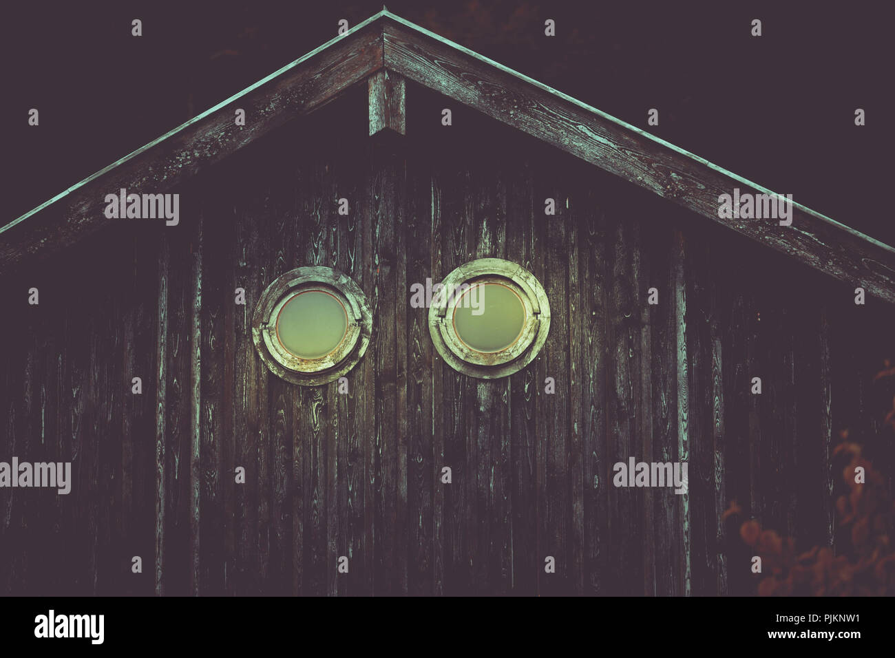 Eine rustikale Holzhütte mit runden Fensteröffnungen, Stockfoto