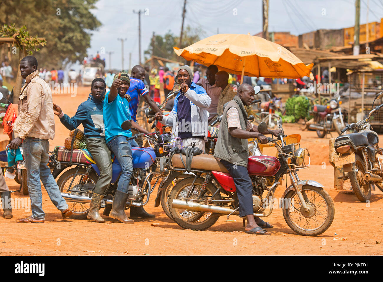 Kleinstadt, Straßenszene, Männer mit Motorrädern, Boda Boda, Motorbike Taxis, Uganda, Ostafrika Stockfoto