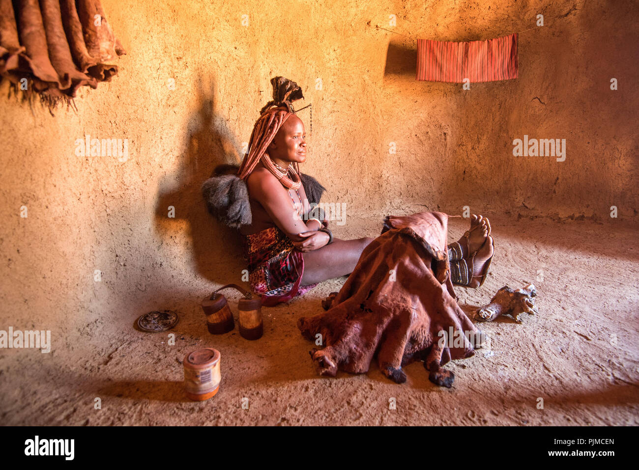 Eine junge Frau Himba zeigt, wie man sie reinigt und Parfums selbst mit Hilfe der aufsteigenden Rauch aus einem Tontopf. Stockfoto