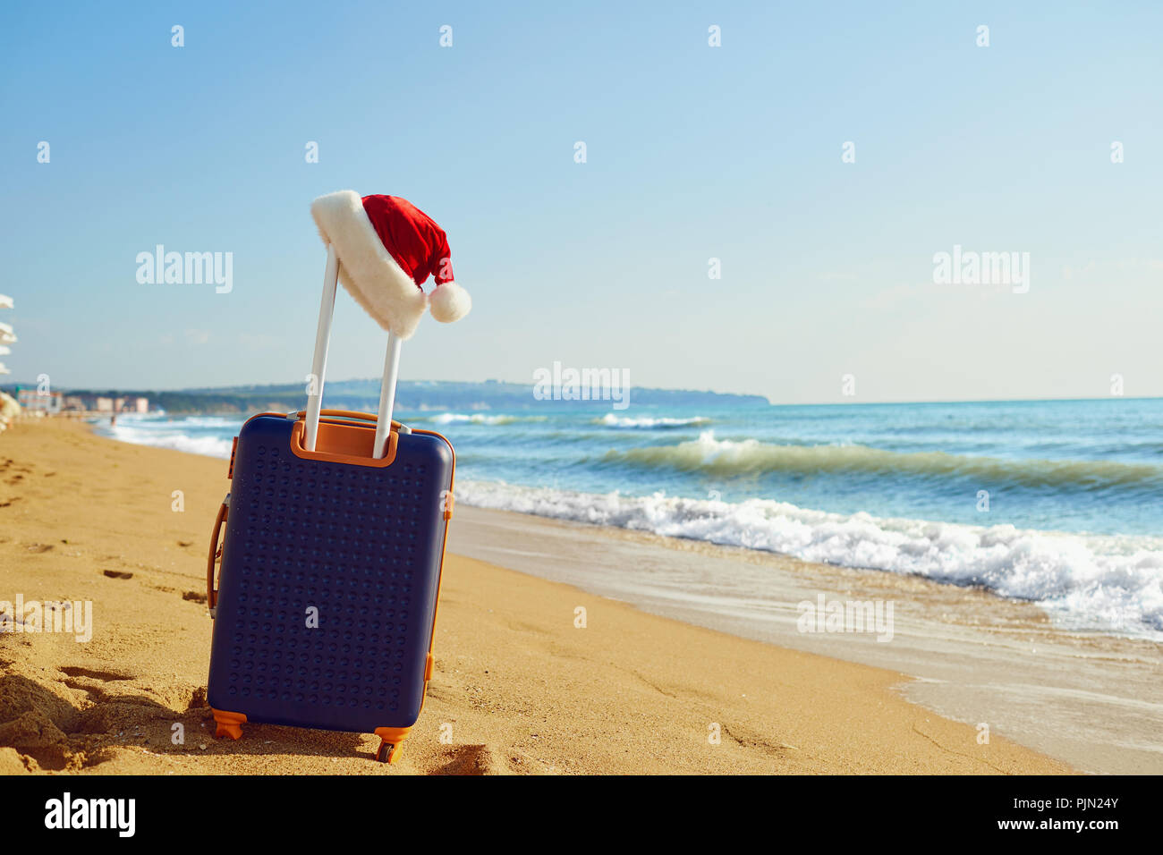 Santa Claus Hut auf einem Koffer auf der Strand am Meer. Weihnachten Stockfoto