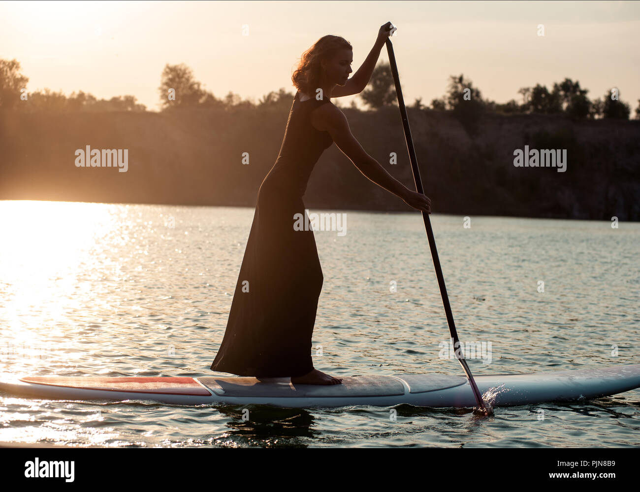 Stand Up Paddle Board von schönen Mädchen am Sonnenuntergang Hintergrund durchgeführt Stockfoto