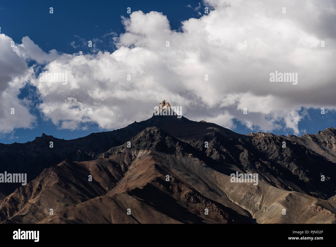 Berglandschaft, mit Sonnenlicht auf Gipfel und blauen Himmel mit weißen Wolken Stockfoto