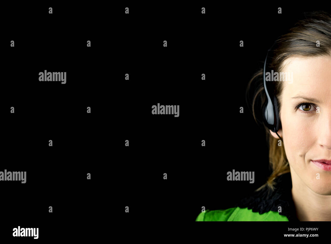 Teilweise mit Blick auf das Gesicht einer attraktiven Frau Headset auf einem dunklen Hintergrund mit Copyspace konzeptionelle einer Call Center, Übersetzer, Rezept Stockfoto