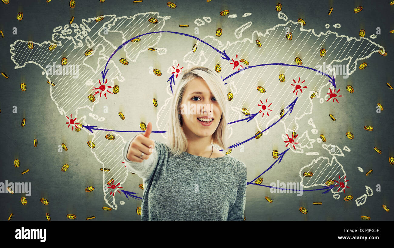 Glückliche junge Frau Daumen hoch, wie Zeichen stehen über Weltkarte Hintergrund und viele goldene Münzen nach unten fallen. Globale virtuelle Währung, Crypto Stockfoto