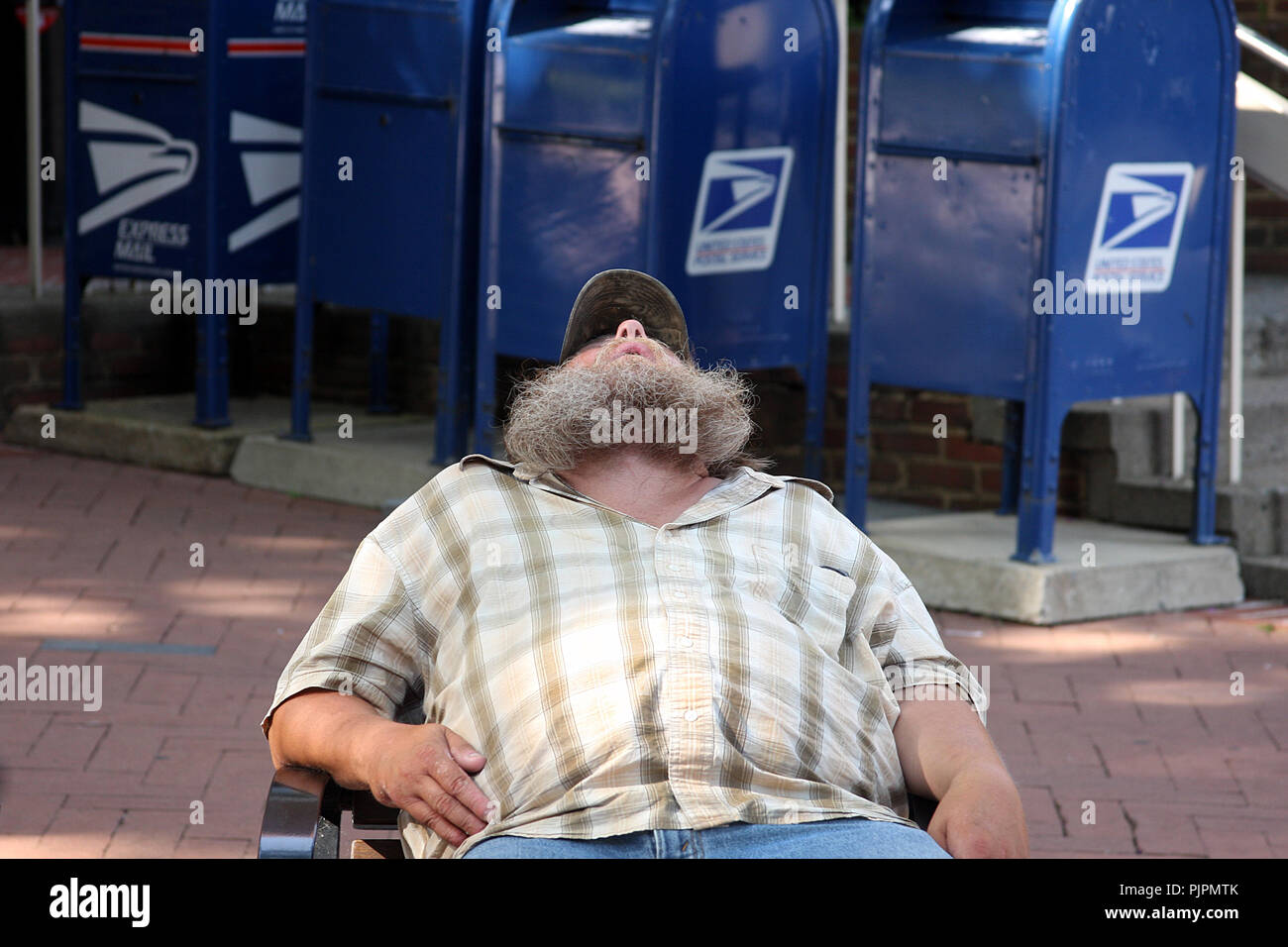 Übergewichtiger Erwachsener, der auf einem Sitz in einem öffentlichen Raum einer US-Stadt ruht Stockfoto