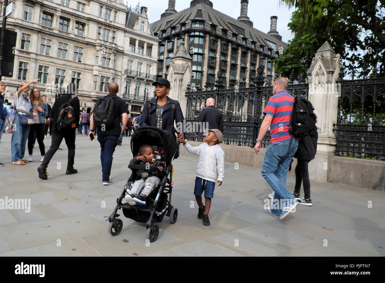 Mutter mit Kindern Kind im Kinderwagen Touristen, die in der Stadtstraße vor den Houses of Parliament Westminster, London England, Großbritannien, KATHY DEWITT, spazieren Stockfoto