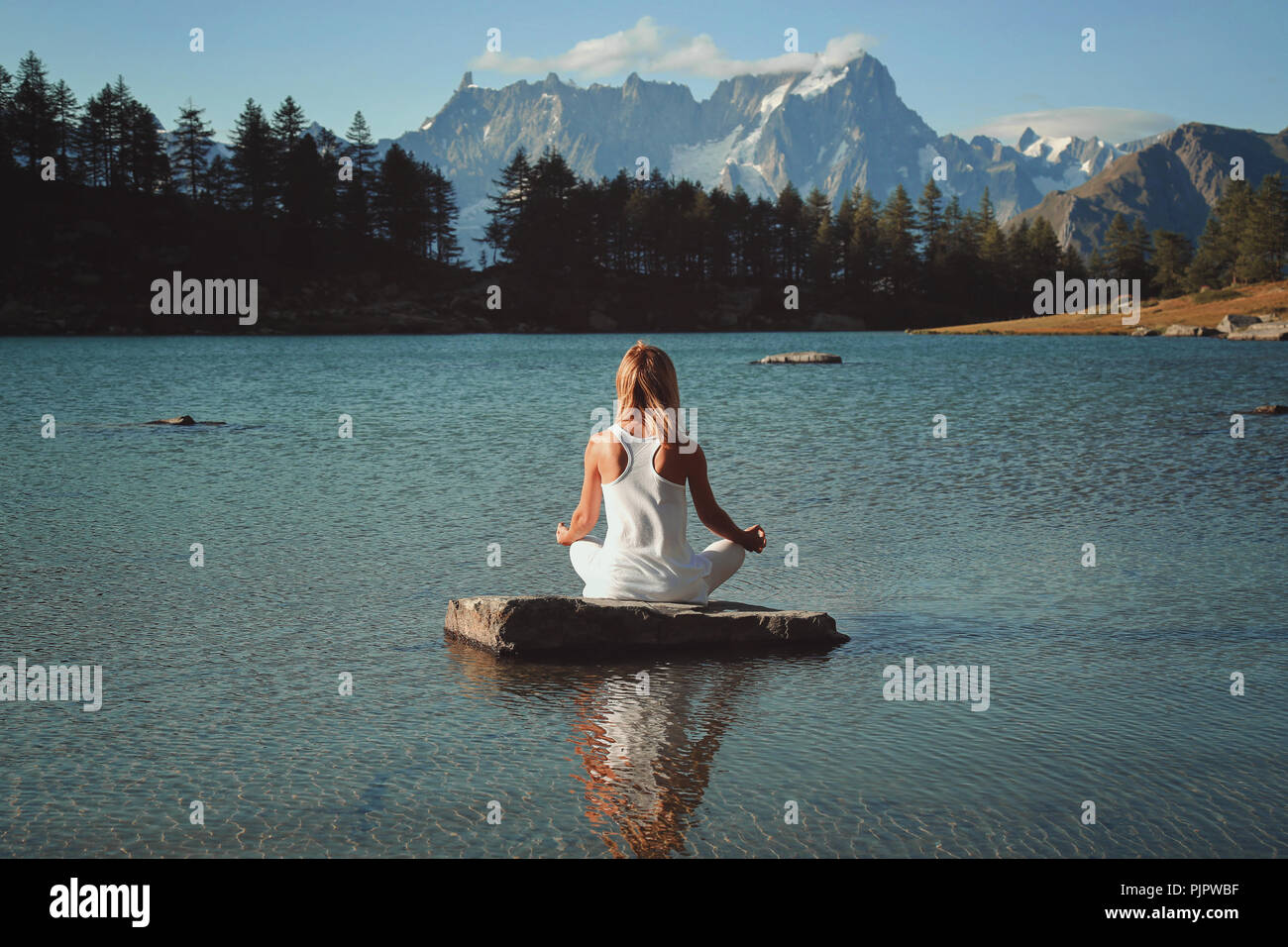 Frau Meditation in Mountain Lake. Lotus Asana Stockfoto