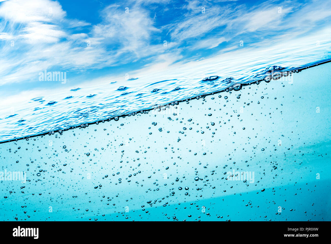 Viele Luftblasen im Wasser ganz nah, abstrakte Wasserwelle mit Luftblasen auf einem Hintergrund des blauen Himmels Stockfoto