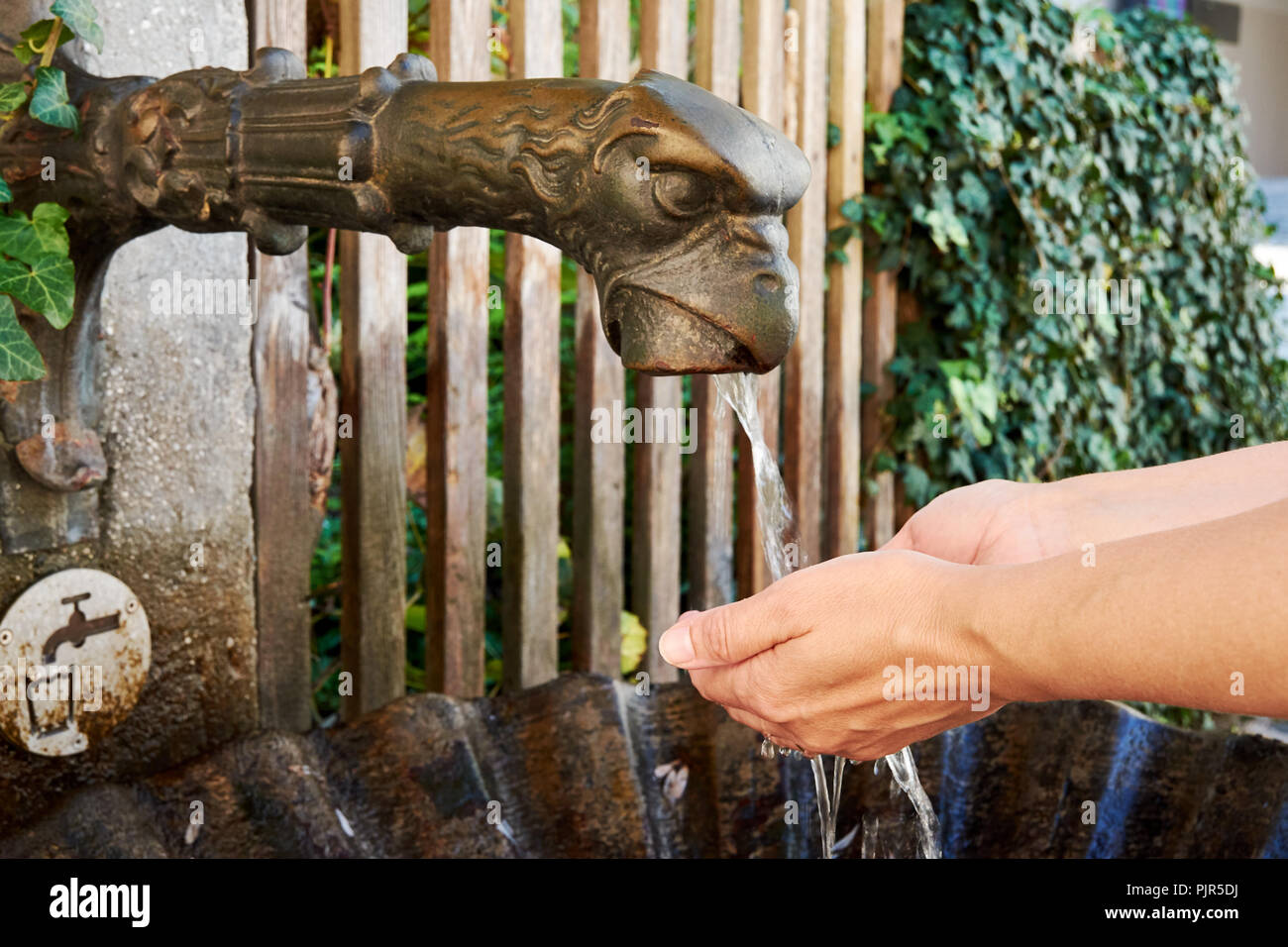 Eine Nahaufnahme eines Bronze Brunnen mit fließendem Wasser in Salzburg und ein trinken Frau ihre Hände waschen - Österreich in Europa Stockfoto