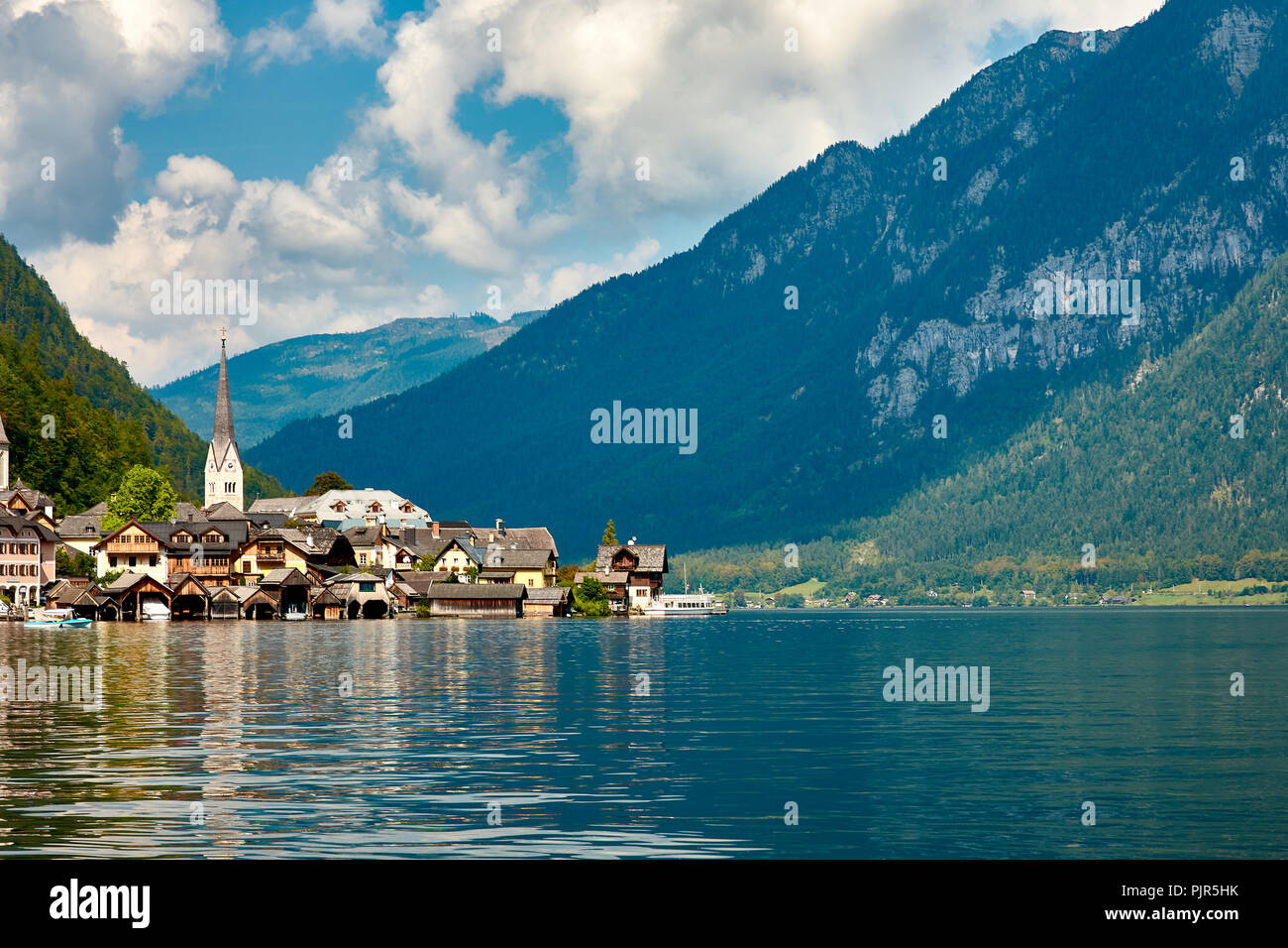 Blick auf die Stadt und den Hallstätter See in Österreich, der Alpen unter einem blauen Himmel mit Wolken und Wald im Hintergrund auf einem hellen und sonnigen Tag Stockfoto