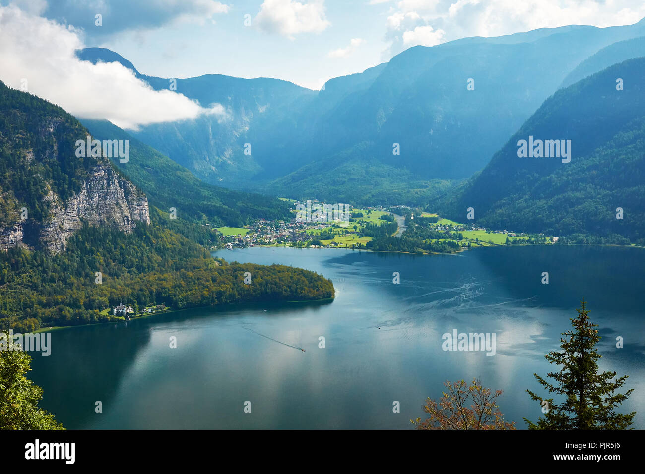 Blick auf die Stadt und den Hallstätter See in Österreich, der Alpen unter einem blauen Himmel mit Wolken und Wald im Hintergrund auf einem hellen und sonnigen Tag Stockfoto