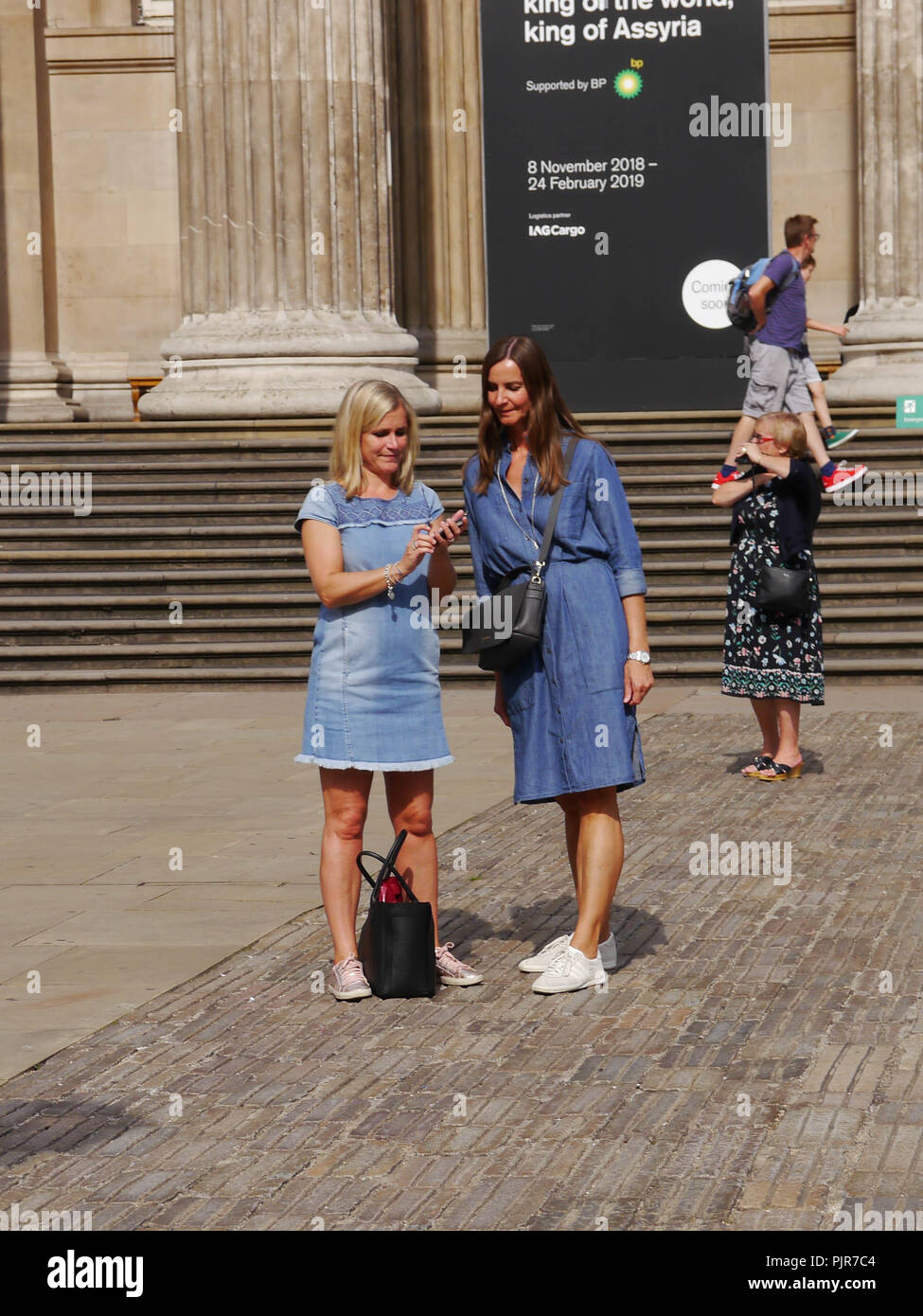 Zwei Damen betrachten Sie Fotos auf Ihrem Telefon außerhalb des British Museum, London, England Stockfoto