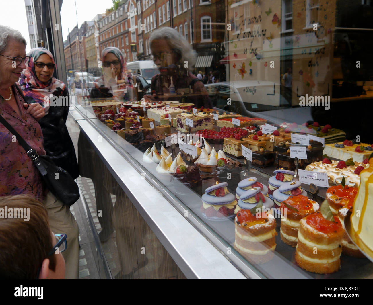 Leute schauen auf Kuchen durch eine Bäckerei Fenster Stockfoto