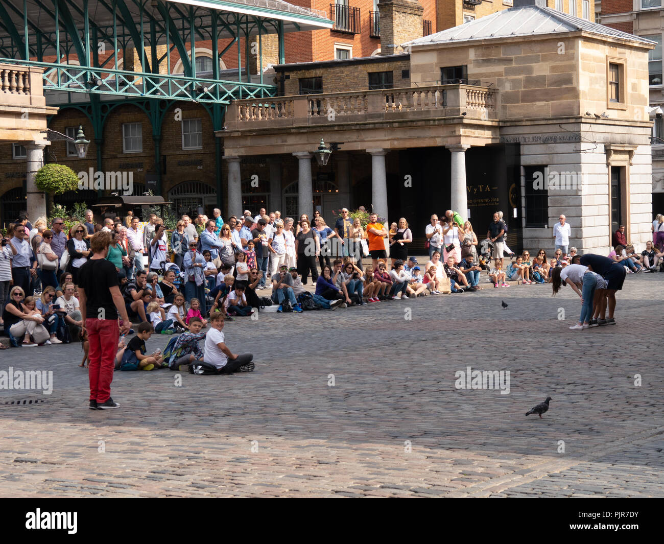 Massen von Menschen sehen eine Straße Leistung in Covent Garden, London, England Stockfoto