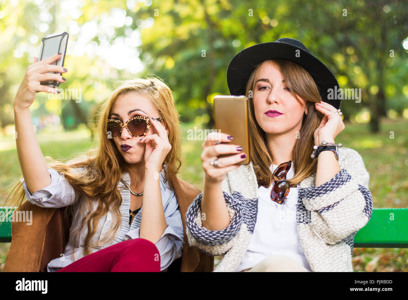 Weibliche Freunde klatschen mit einem Telefon im Park Stockfoto