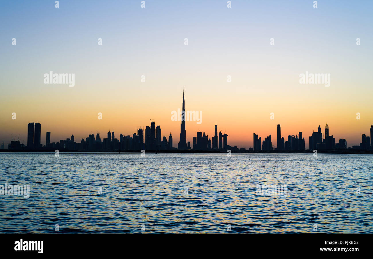 Panoramablick auf Dubai Stadtbild über Wasser bei Sonnenuntergang Stockfoto