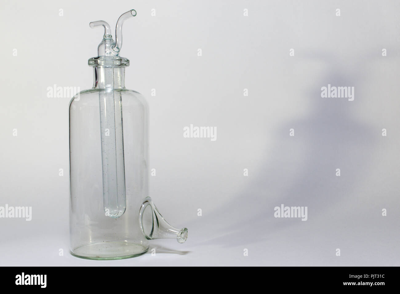 Wasser gefüllt composite Reagenzglas mit zwei gebogenen Rohre, aus der Oberseite, auf leeren Laborflasche mit seitlichen Trunk (Tipp) auf flachem Boden. Stockfoto