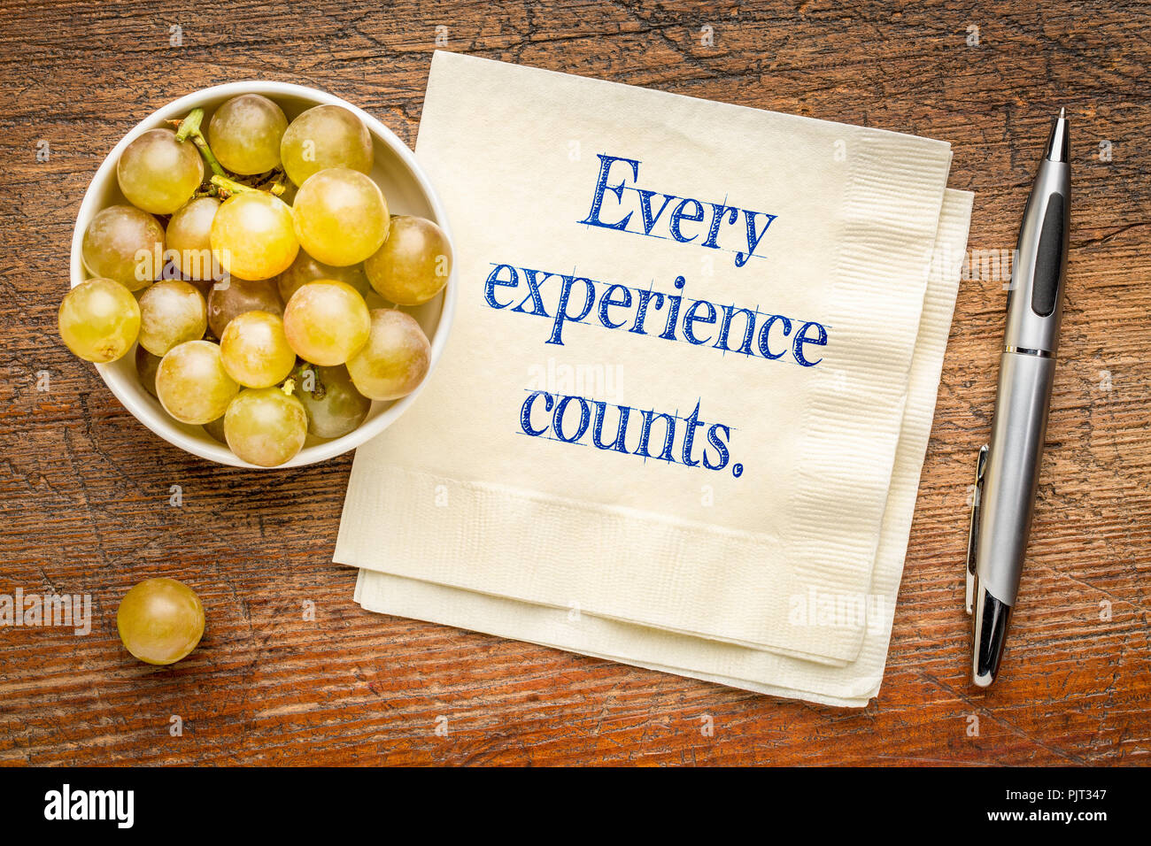 Jede Erfahrung zählt Erinnerung - Handschrift auf eine Serviette mit frischen Weintrauben Stockfoto