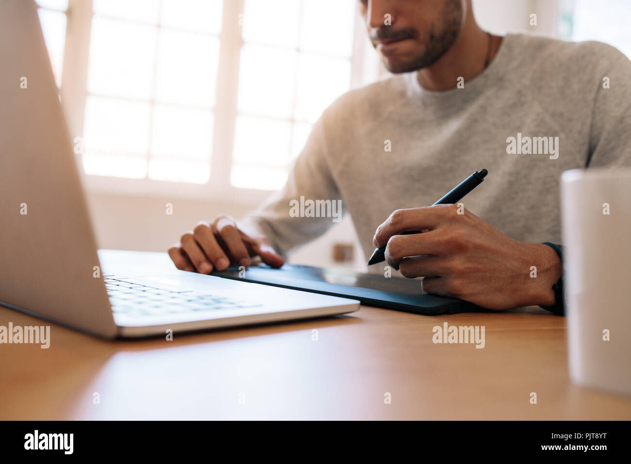 Mann schreiben auf eine digitale Schreibunterlage mit einem Laptop sitzen auf einem Tisch im Büro verbunden. Mann schreiben auf eine elektronische Schreibblock mit Digital Pen. Stockfoto