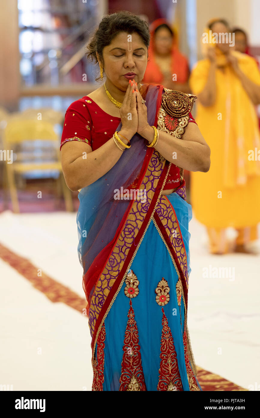 Eine dreiviertel länge Porträt einer hinduistischen Frau zu beten und meditieren an einem Tempel in South Richmond Hill, Queens, New York City. Stockfoto