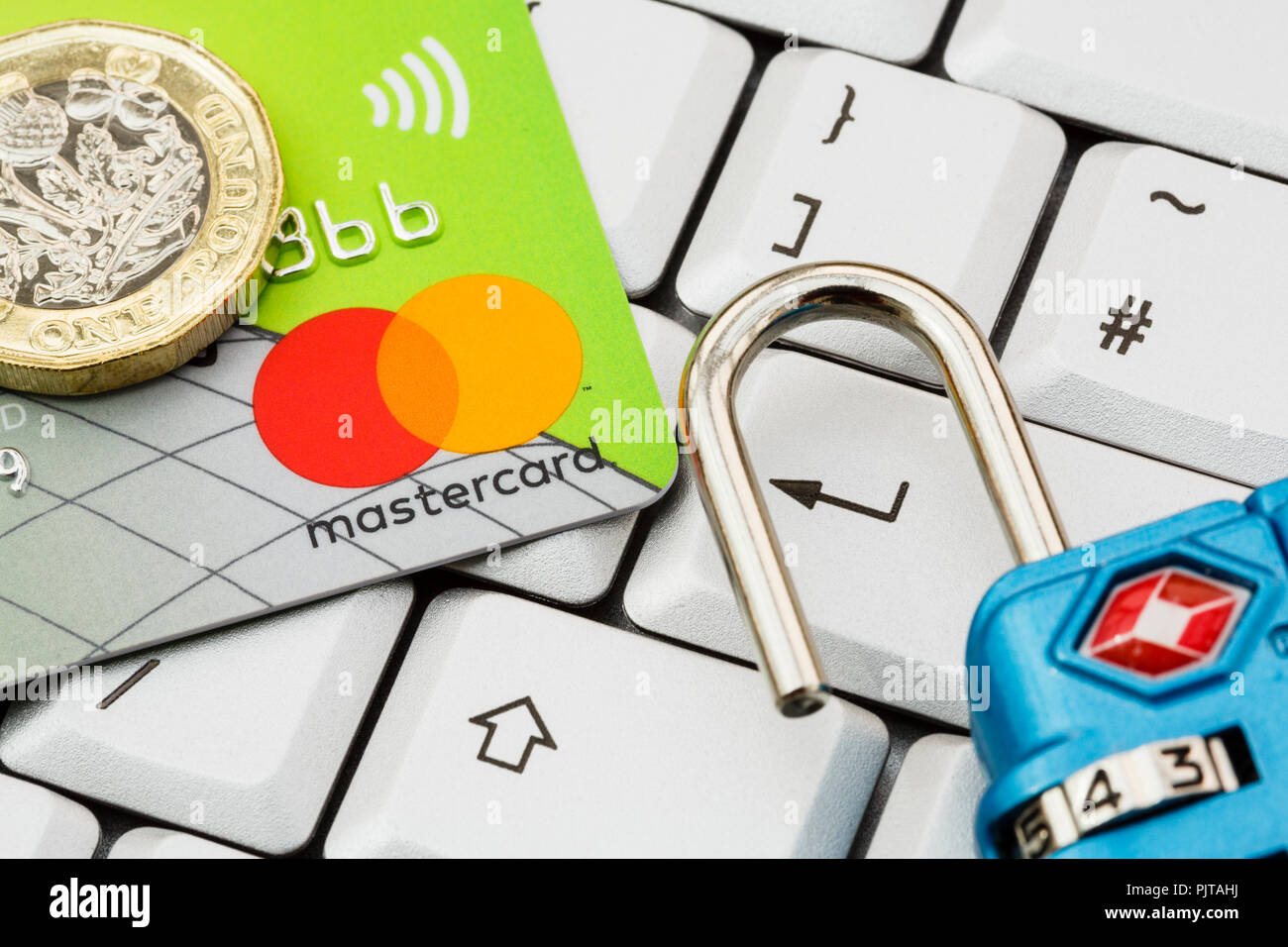 Lloyds Bank Mastercard Kontaktlose Kreditkarte und Einpfundstück auf einer Tastatur mit Enter-taste und Schloss geöffnet. Online shopping Sicherheitskonzept. Großbritannien Stockfoto