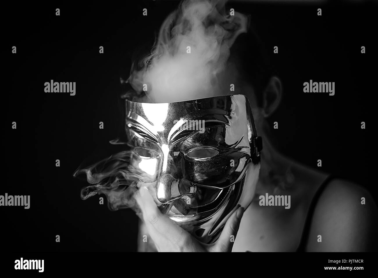 Studio Porträt einer Frau, die ihr Gesicht verbergen Mit einem anonymen Stil Maske mit Rauch Weglassen von hinten Stockfoto