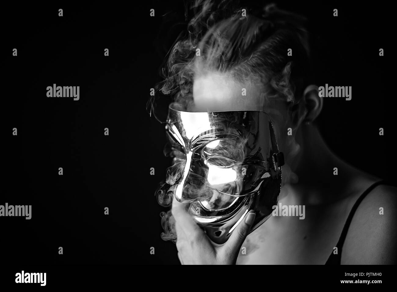 Studio Porträt einer Frau, die ihr Gesicht verbergen Mit einem anonymen Stil Maske mit Rauch Weglassen von hinten Stockfoto